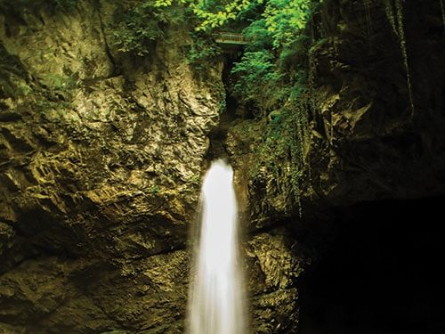 Chute d'eau souterraine illuminée dans une grotte.