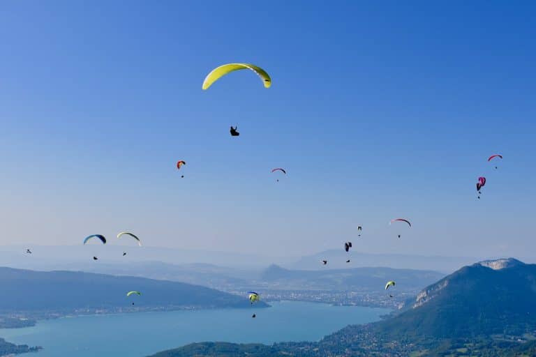 Parapentistes au-dessus d'un lac et montagnes.